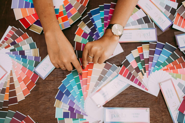 An overhead shot of a person's hands with many color swatches fanned out around them