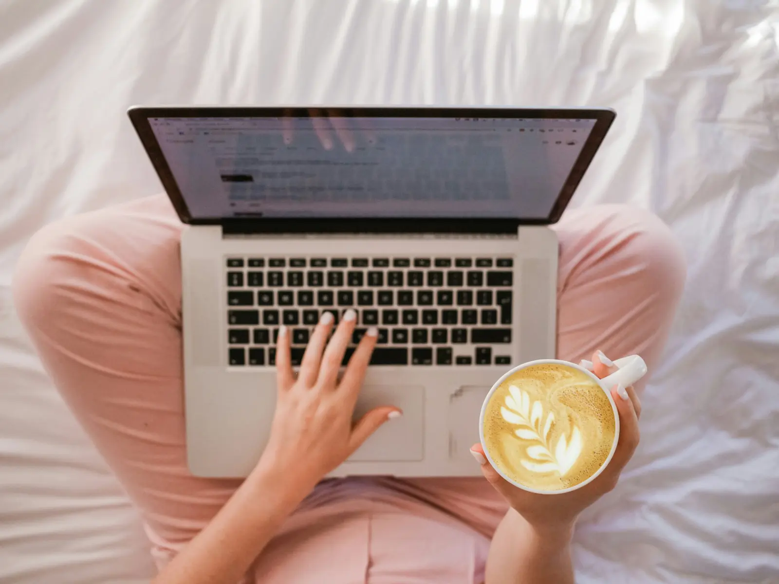 Woman working on laptop and holding coffee. Photo by Sincerely Media on Unsplash