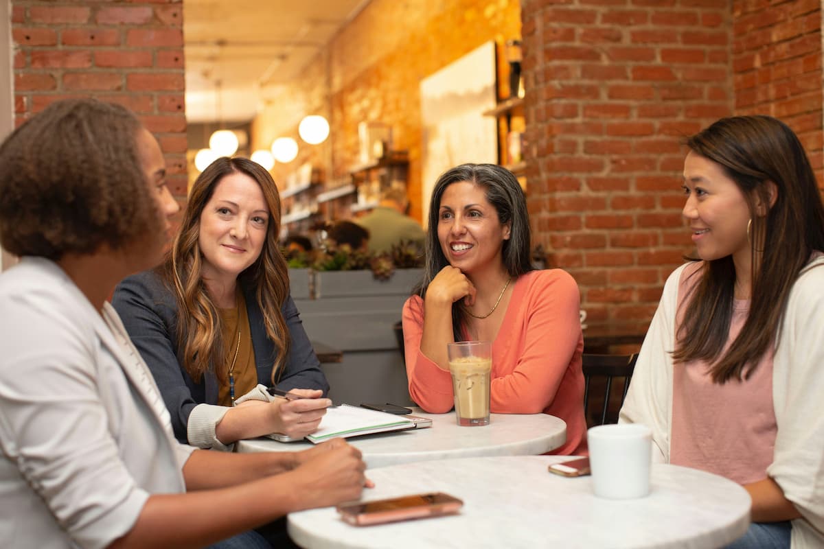 Four women sitting at a table networking. Photo by LinkedIn Sales Solutions on Unsplash.